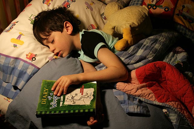 Child fell asleep in bed reading "Diary of a Wimpy Kid."